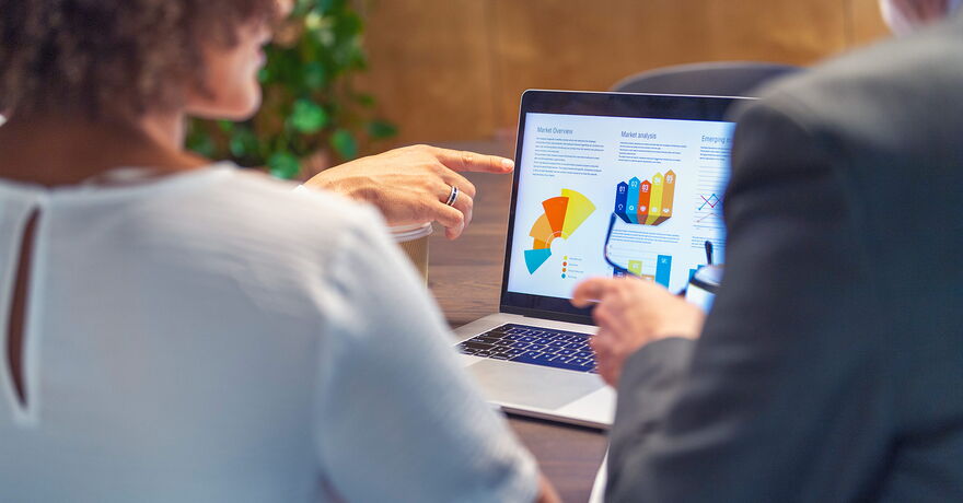Zwei Personen schauen sich eine Grafik auf einem Laptop an